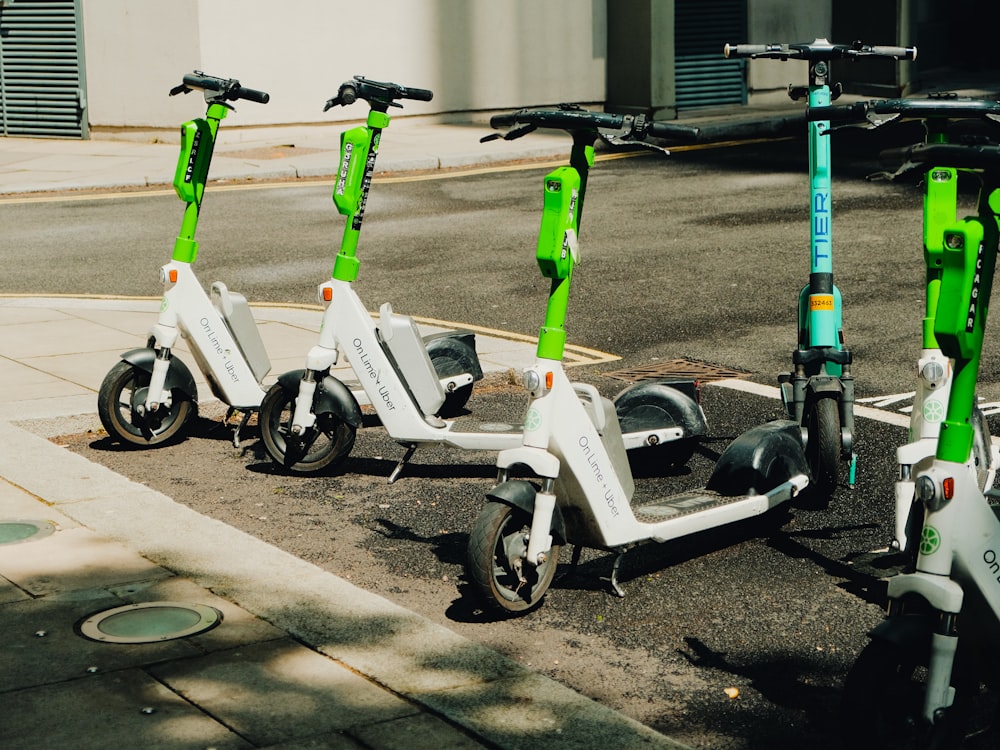 three electric scooters parked on the side of the road