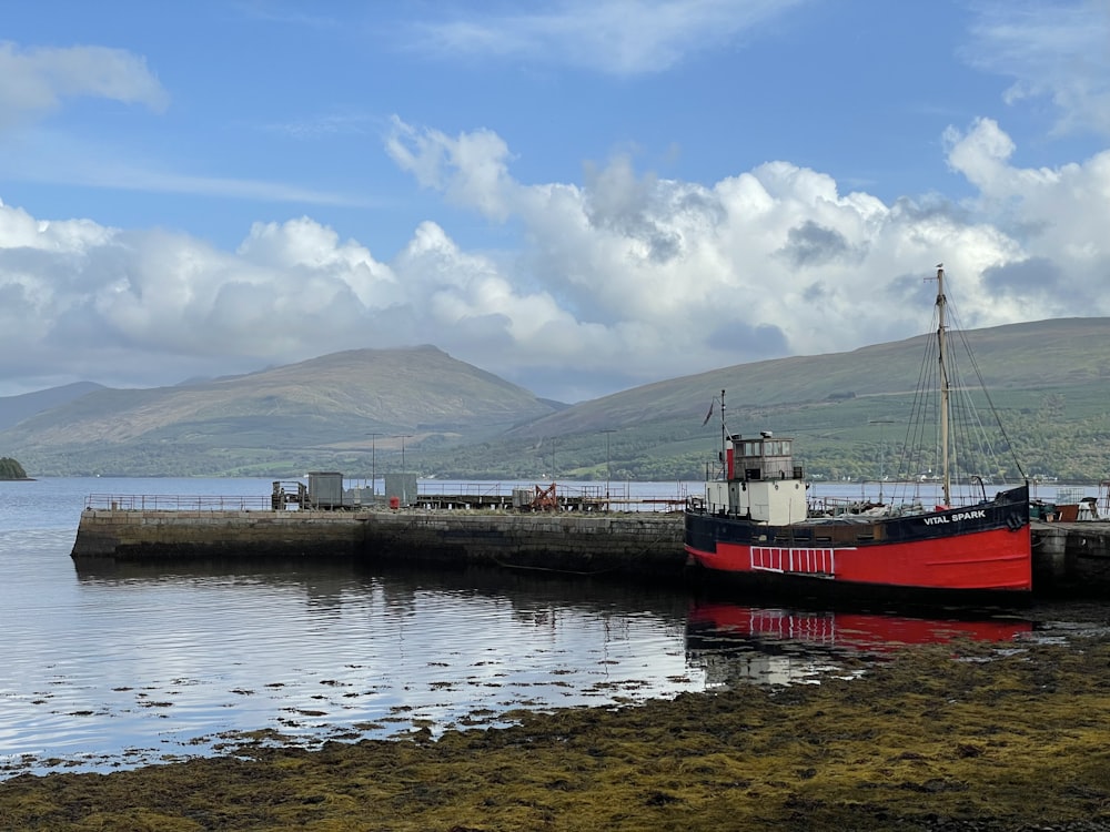 a red and white boat sitting on top of a body of water