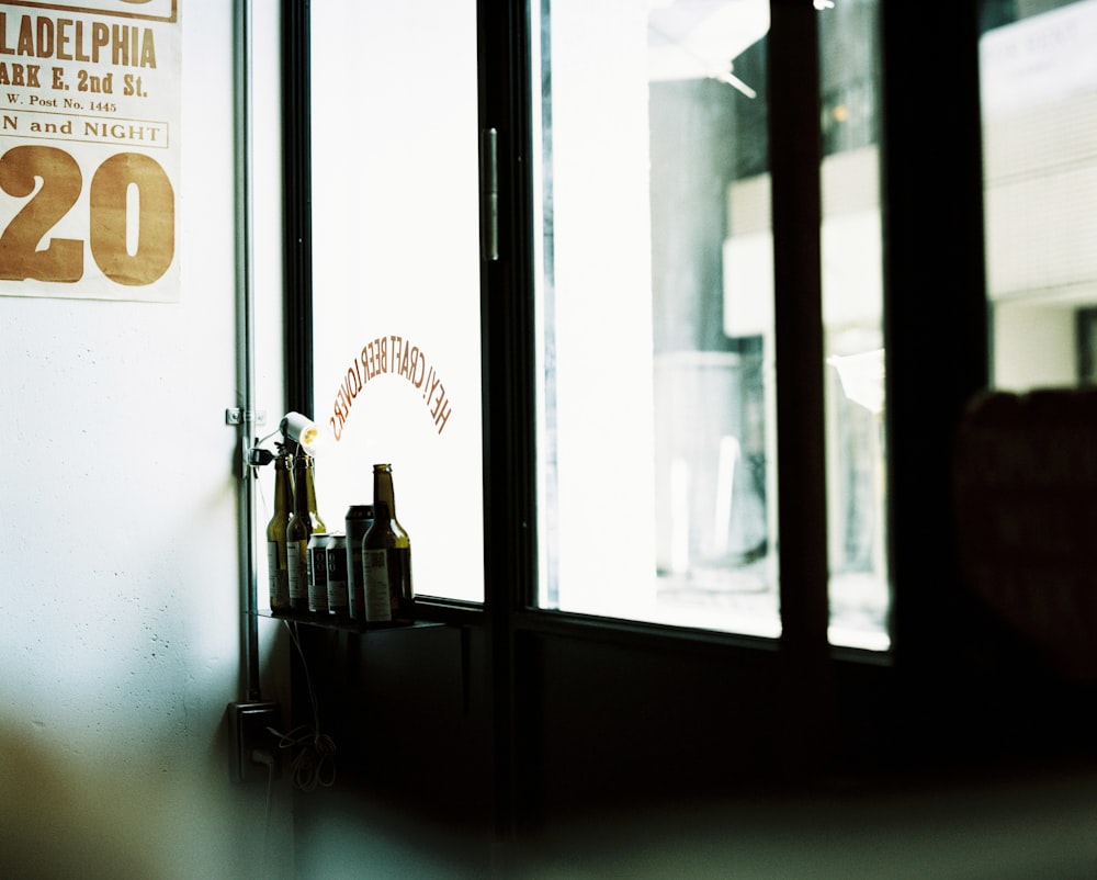 there are bottles of beer on a shelf in front of a window