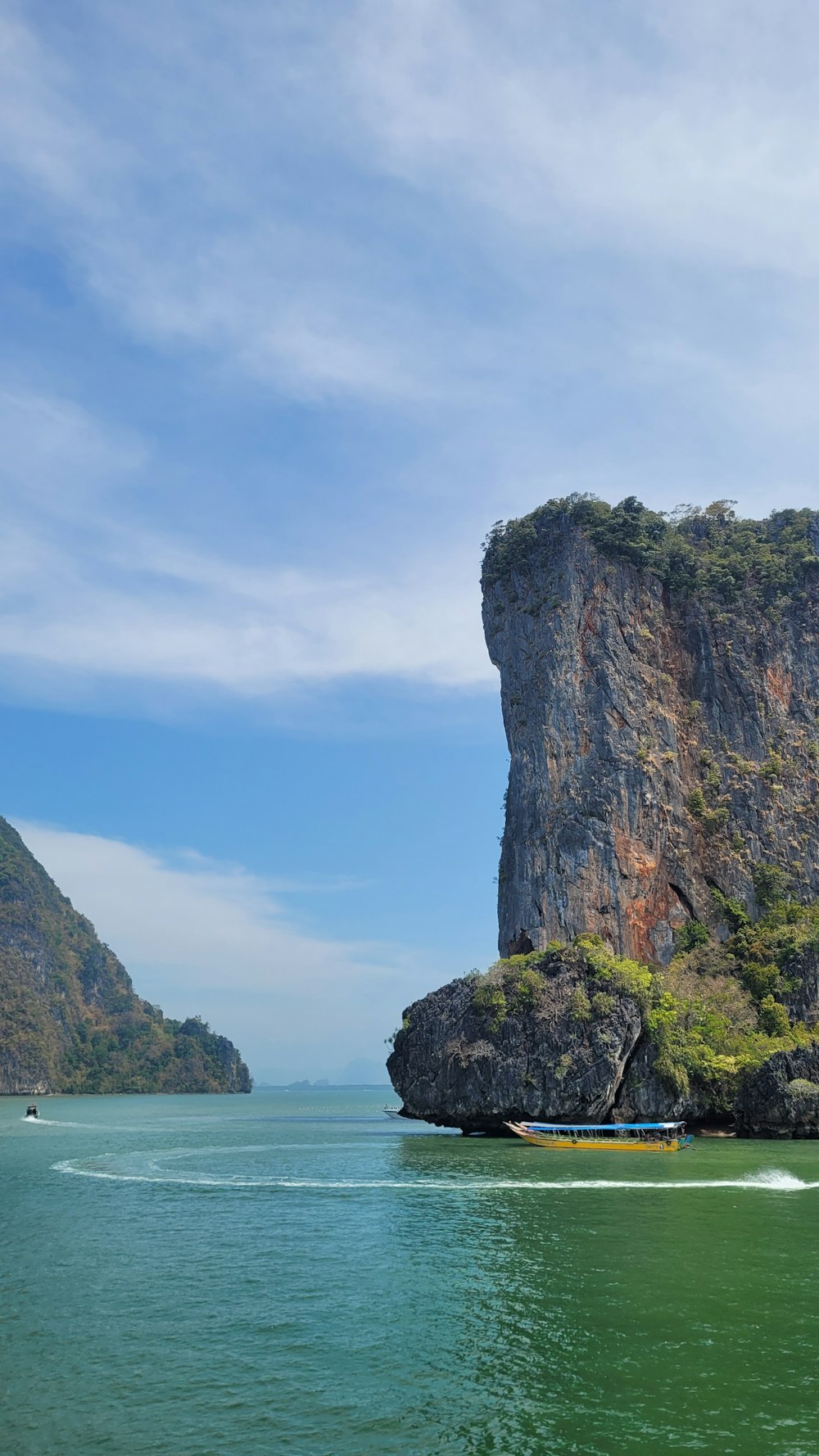 a boat traveling through a body of water next to a mountain