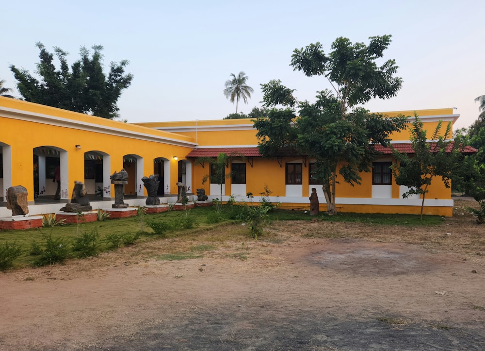 a yellow and white building with trees in front of it