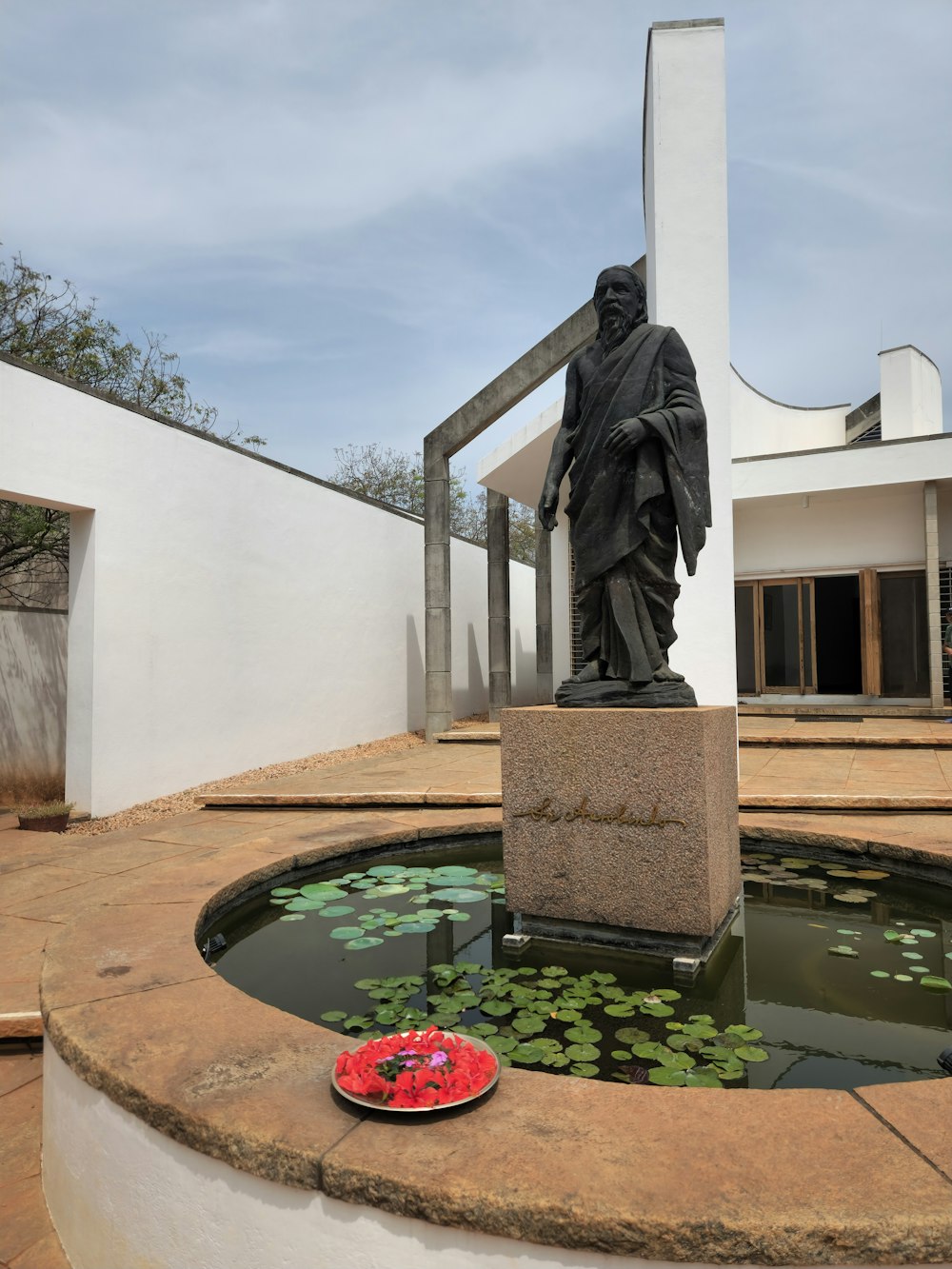 eine Statue eines Mannes, der neben einem Teich steht