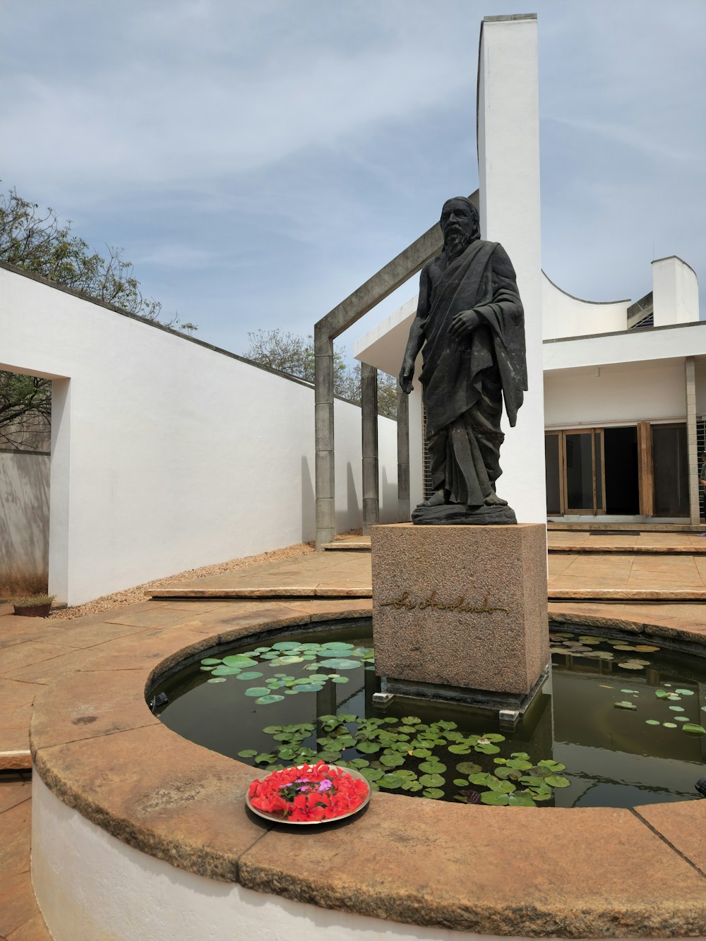 a statue of a man standing next to a pond