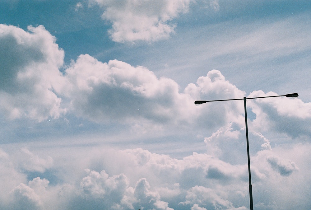 a street light on a pole in front of a cloudy sky