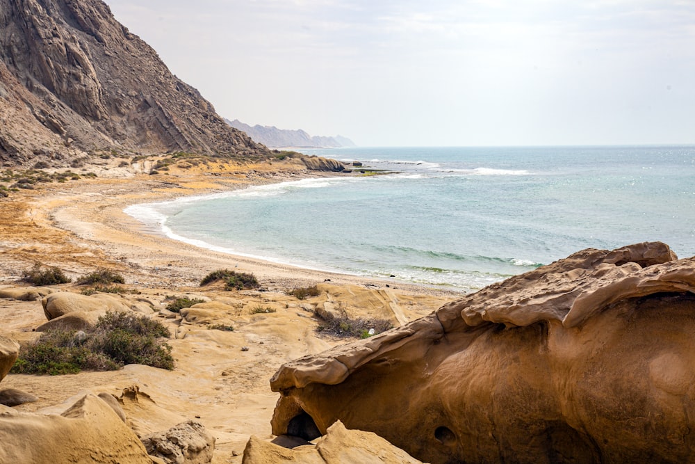una playa rocosa con un cuerpo de agua al fondo