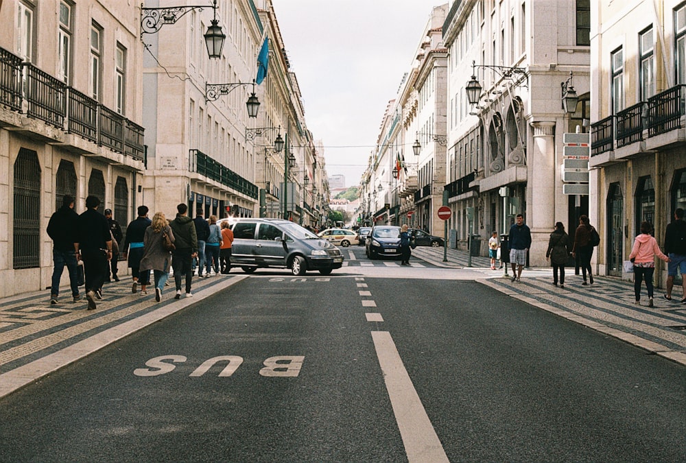 a group of people walking down a street next to tall buildings