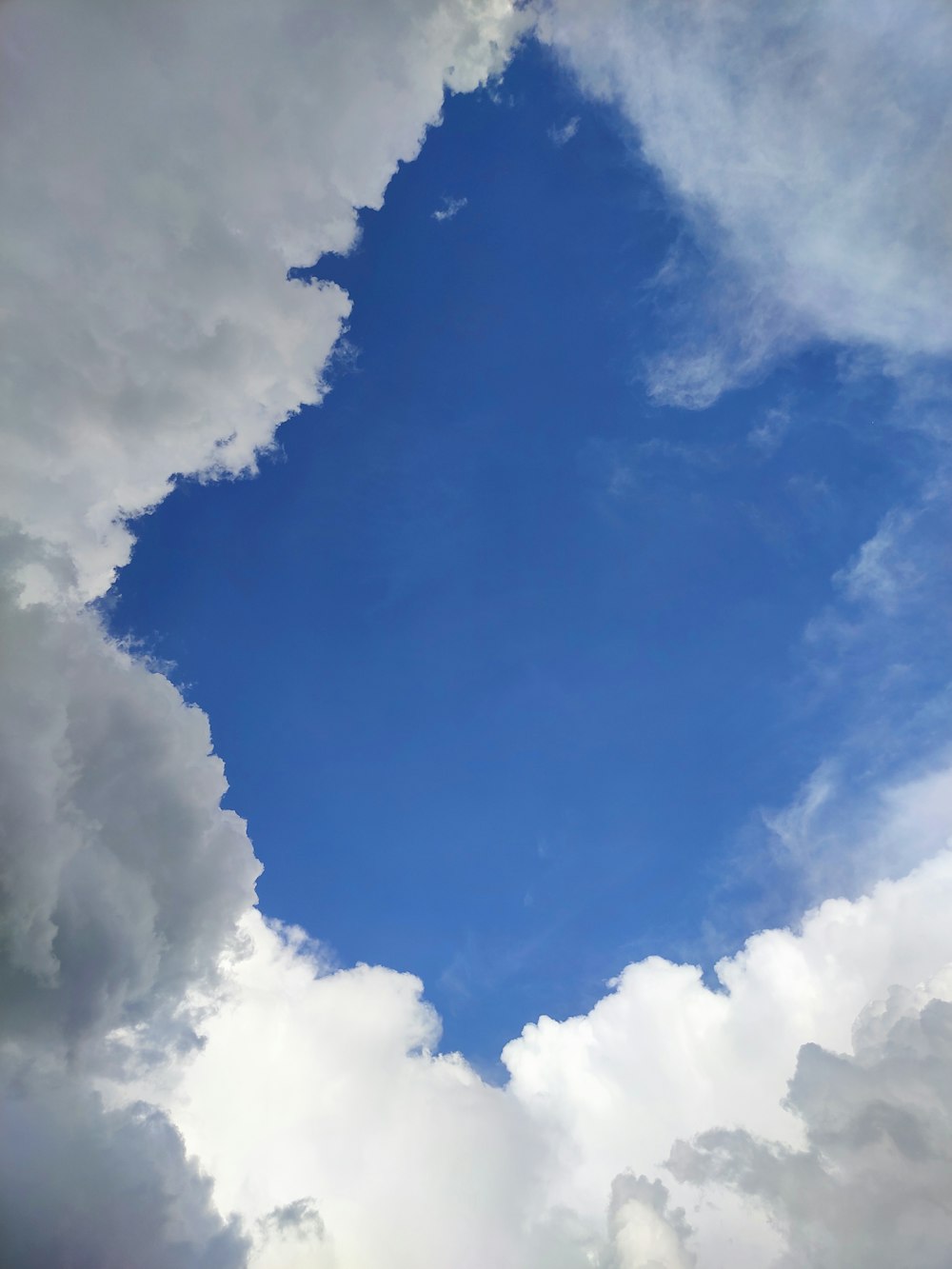 a plane flying through a cloudy blue sky