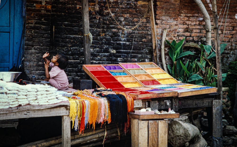 a woman sitting on a bench next to a colorful table