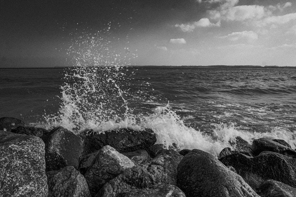 Una foto in bianco e nero delle onde che si infrangono sugli scogli