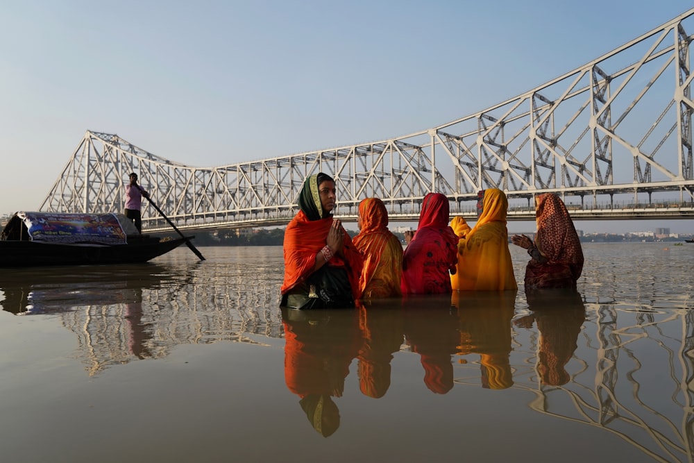 a group of women sitting on the side of a river