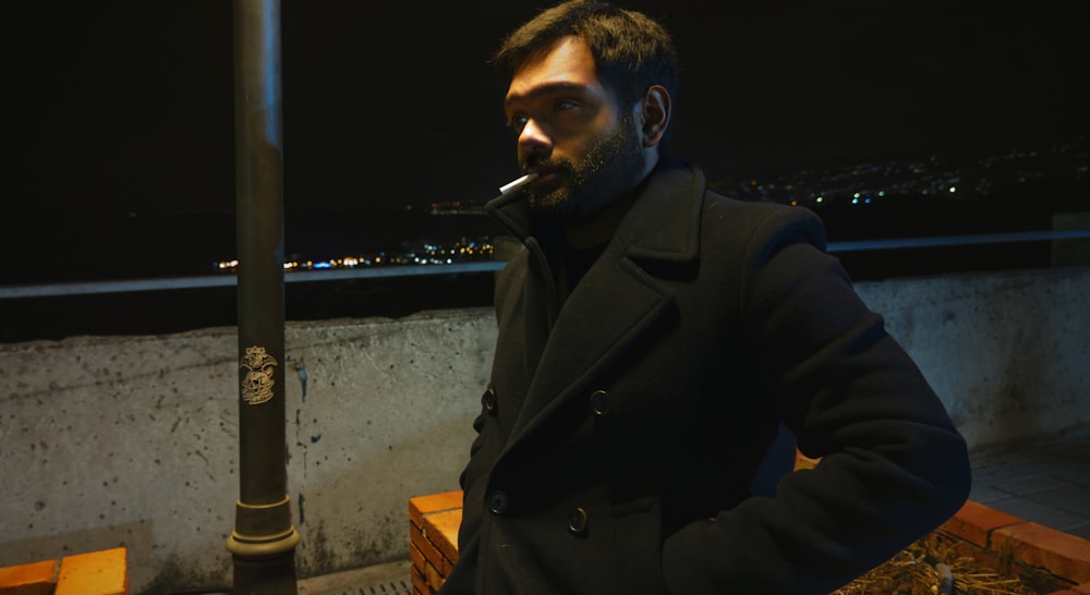 Un hombre con abrigo fumando un cigarrillo