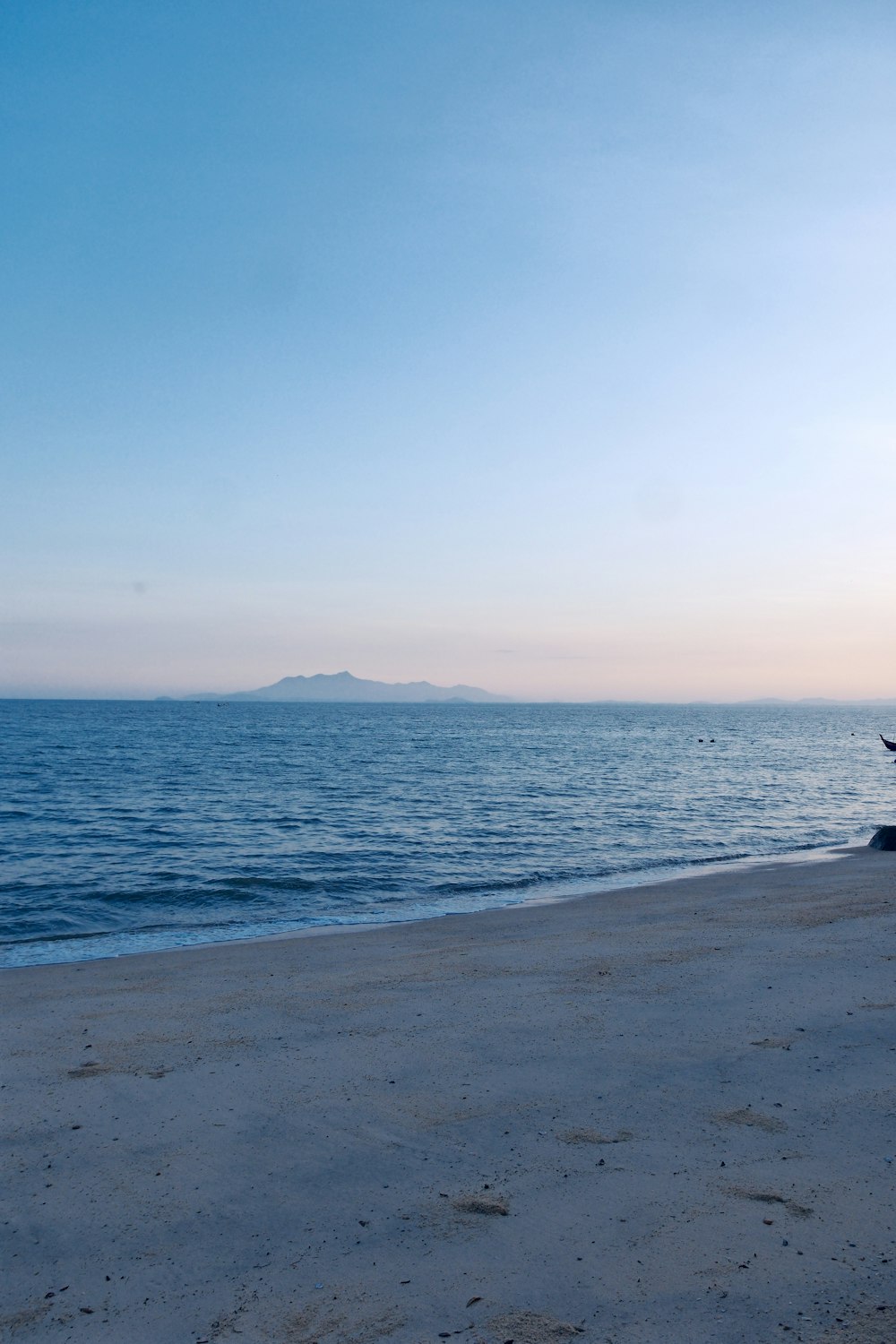 a boat sitting on top of a beach next to the ocean