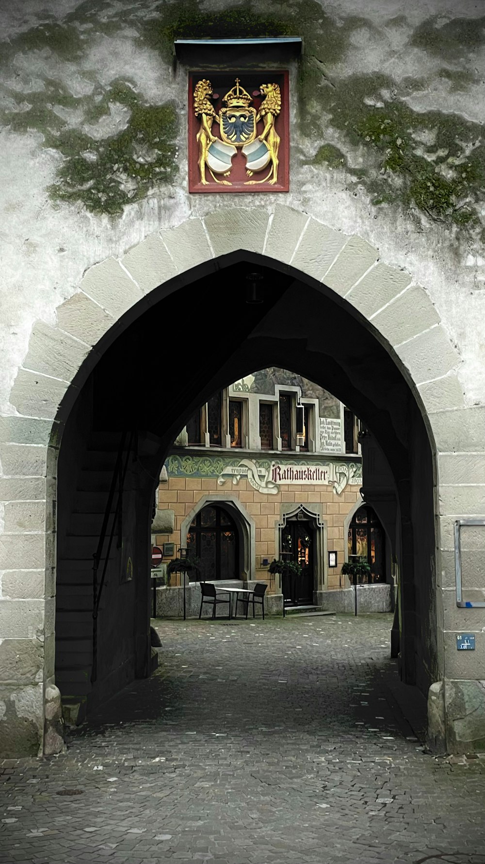 an archway leading to a building with a coat of arms on it