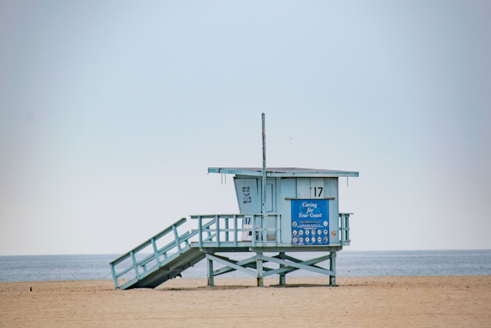 una torretta di salvataggio sulla spiaggia con un cartello blu su di esso