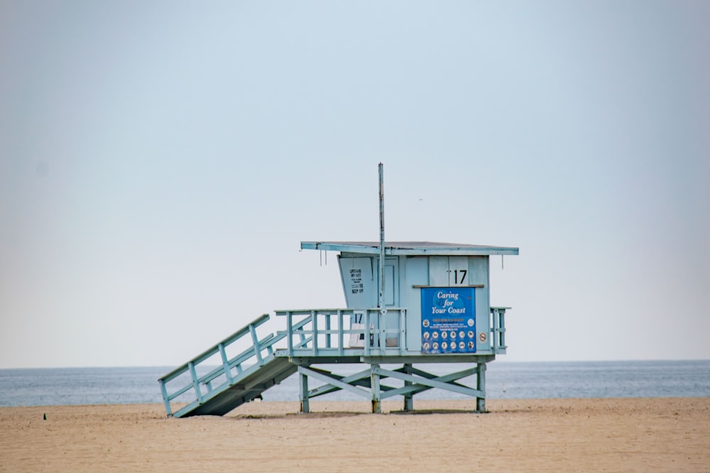 a lifeguard tower on the beach with a blue sign on it