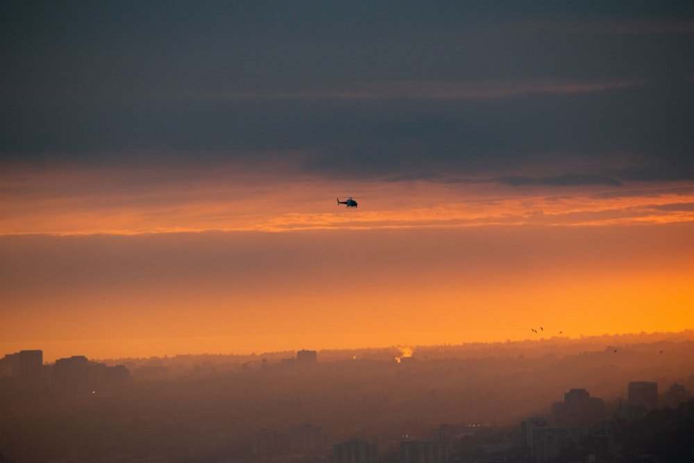 a plane flying over a city at sunset