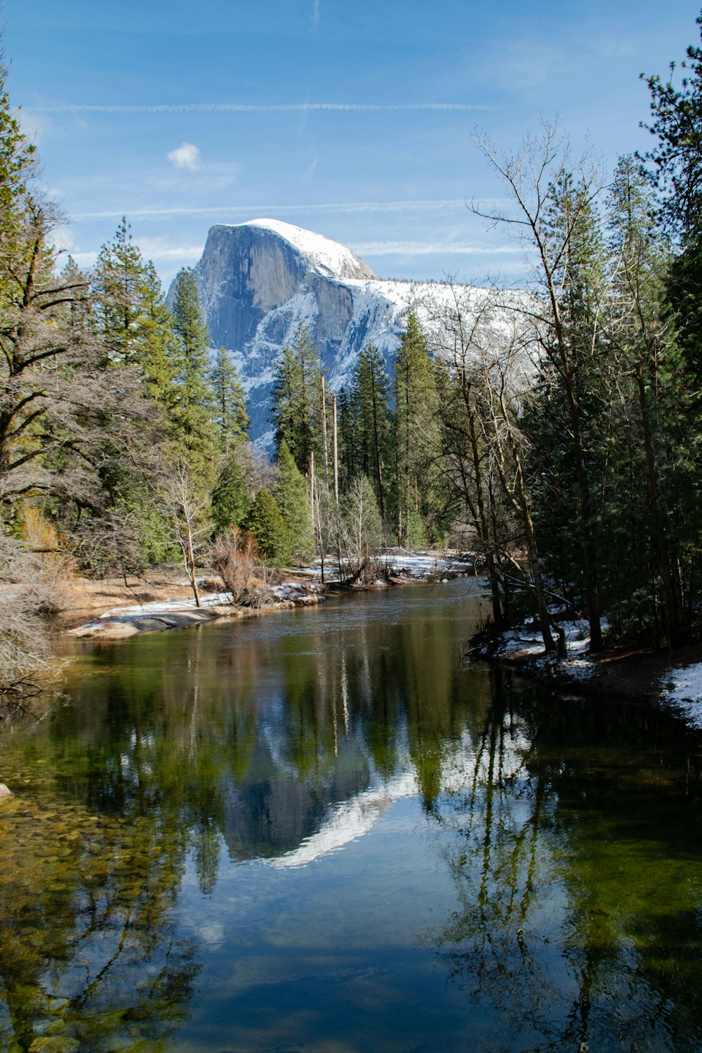 a lake surrounded by trees and snow covered mountains