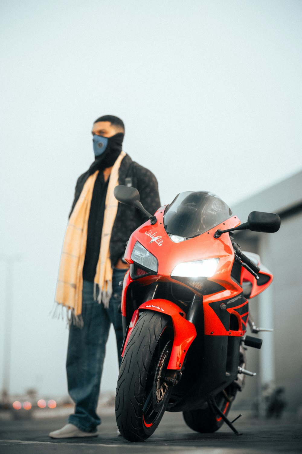 a man standing next to a red motorcycle