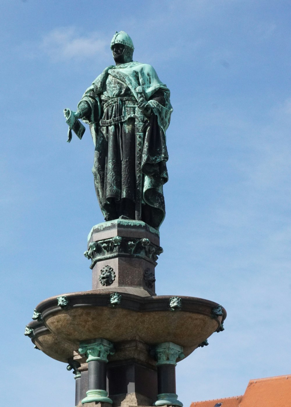 une statue d’un homme debout au sommet d’une fontaine