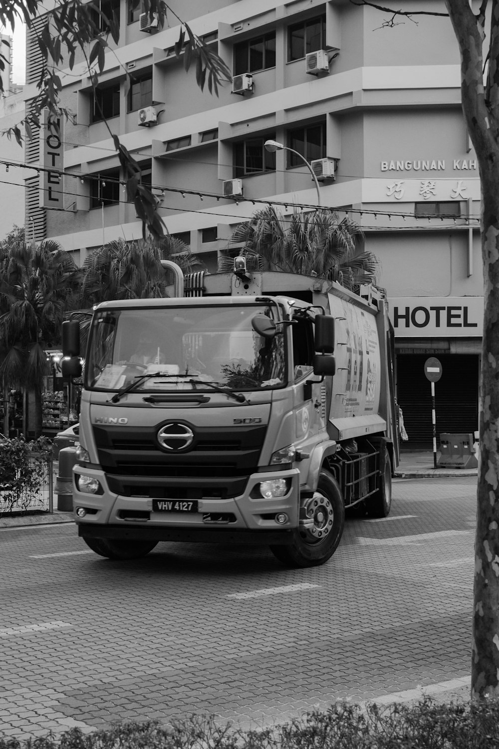 uma foto em preto e branco de um caminhão dirigindo por uma rua