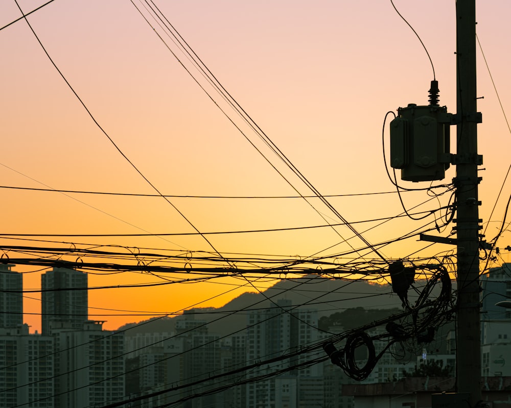 the sun is setting over a city with power lines in the foreground
