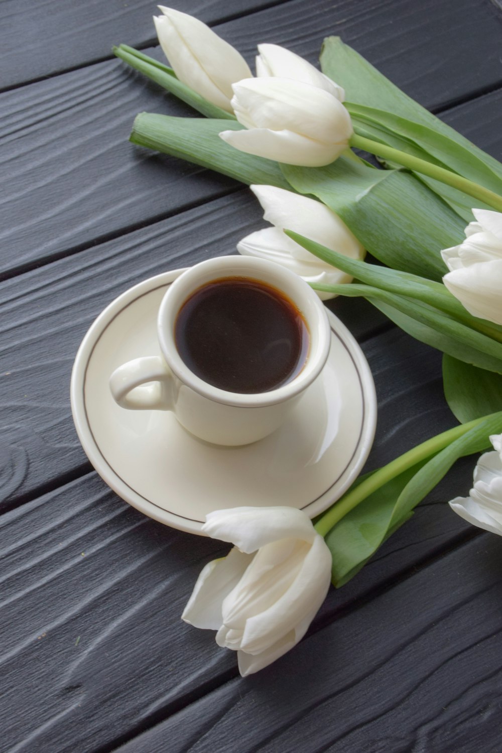 a cup of coffee and some white tulips