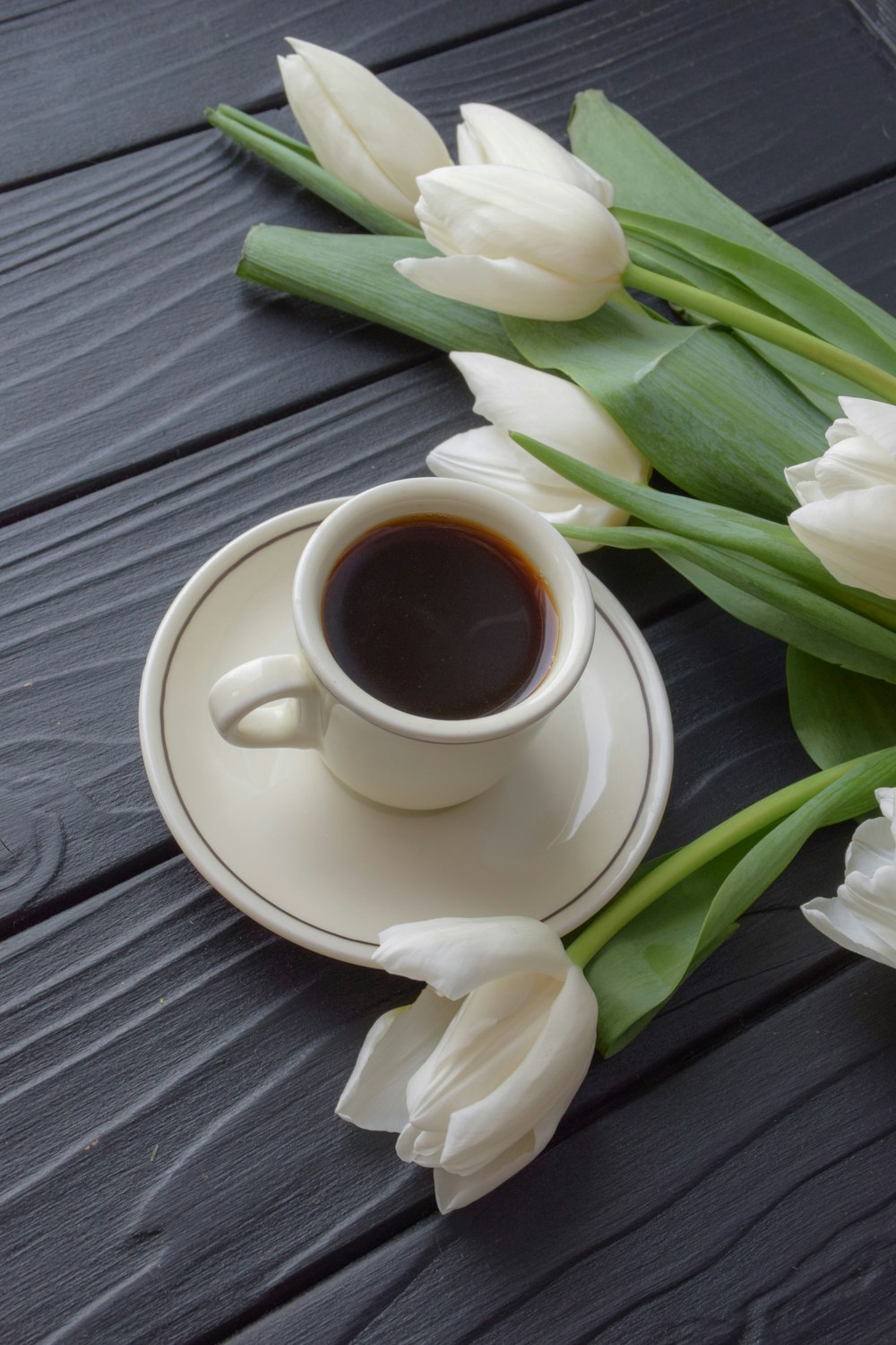 a cup of coffee and some white tulips