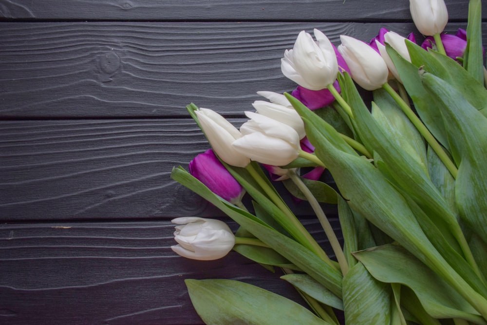 a bouquet of white and purple tulips on a wooden table