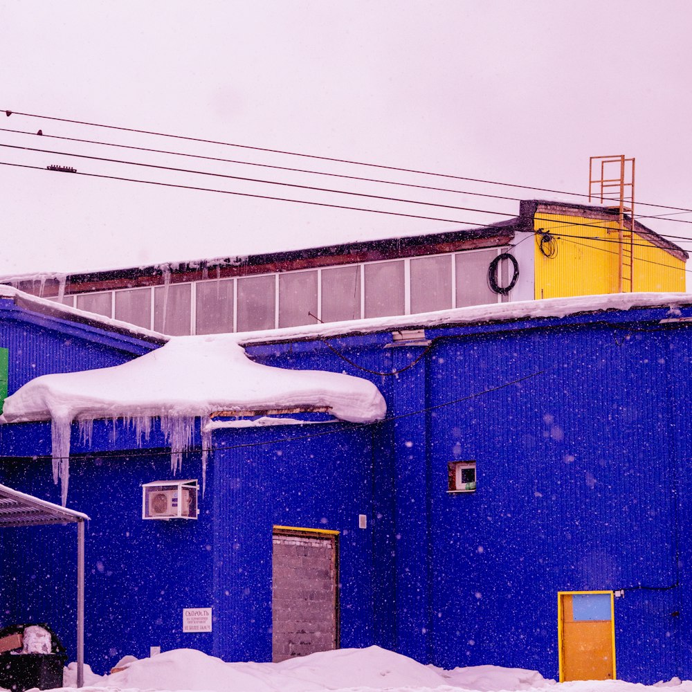 a blue building with snow on the roof