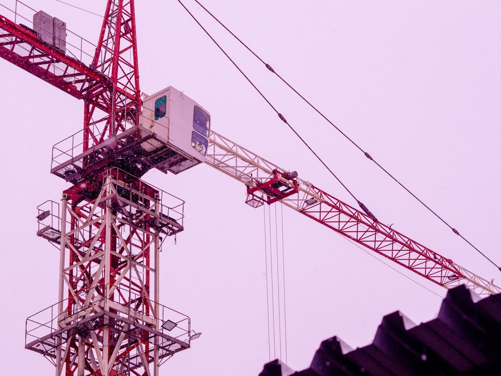 a red crane sitting on top of a building next to power lines