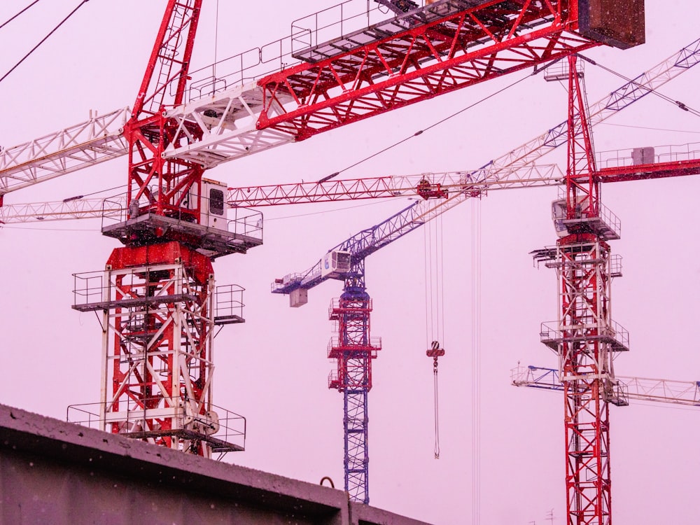 a group of red and white cranes sitting on top of a building