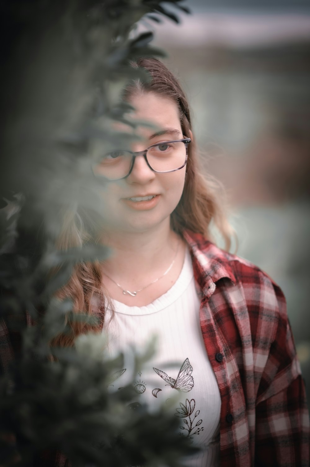 a woman wearing glasses looking through a tree