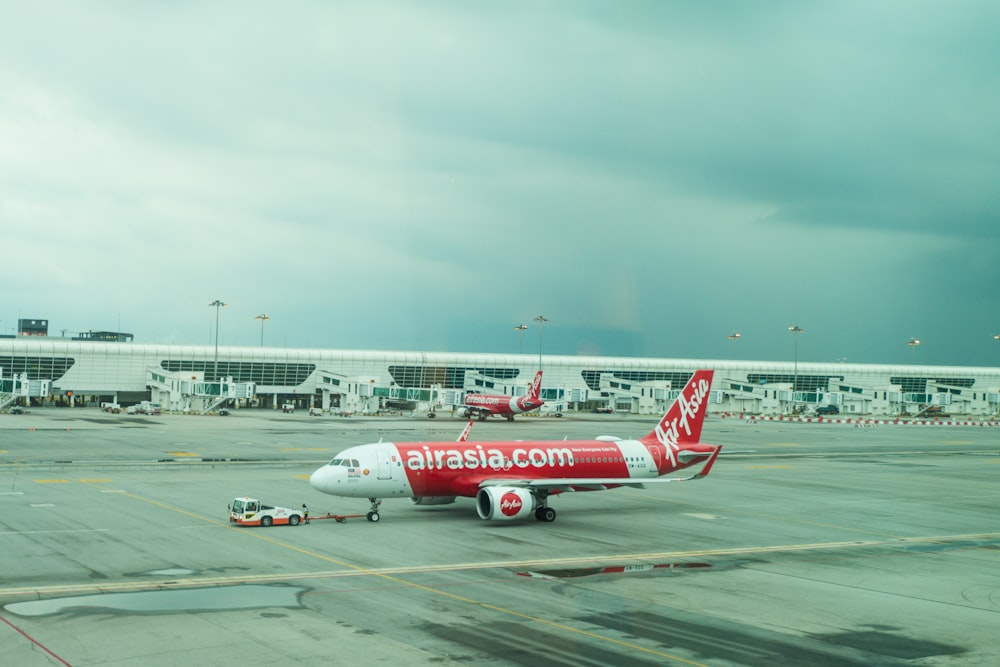 a red and white plane is on the runway