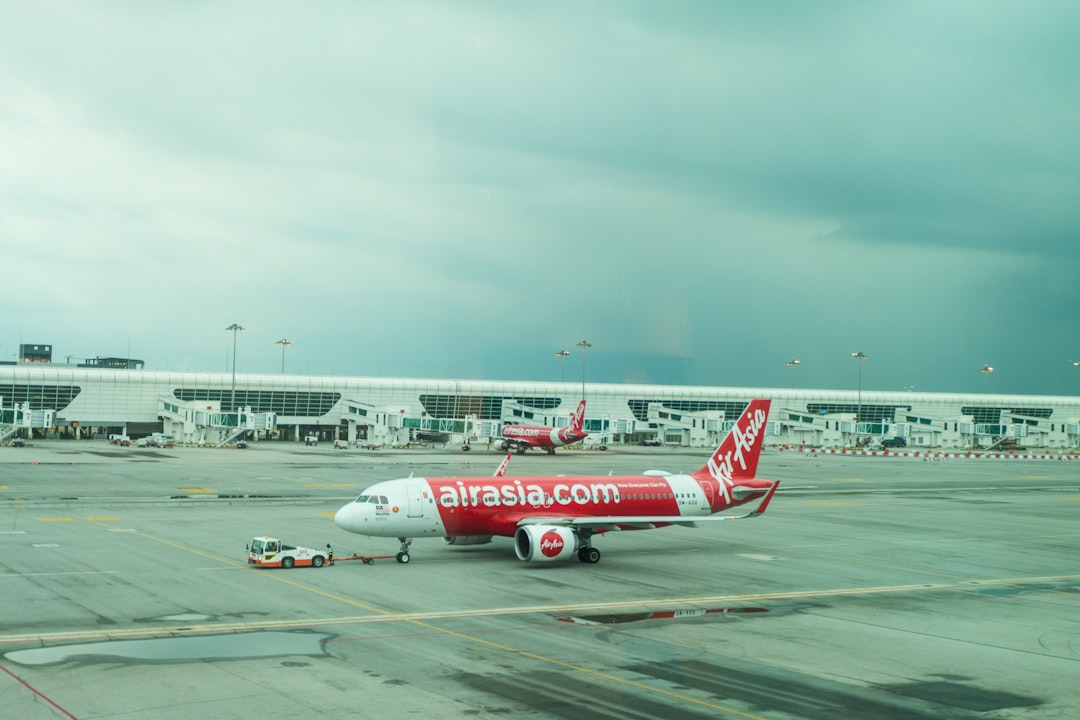 a red and white plane is on the runway, Air Asia plane at KLIA2 Selangor Malaysia