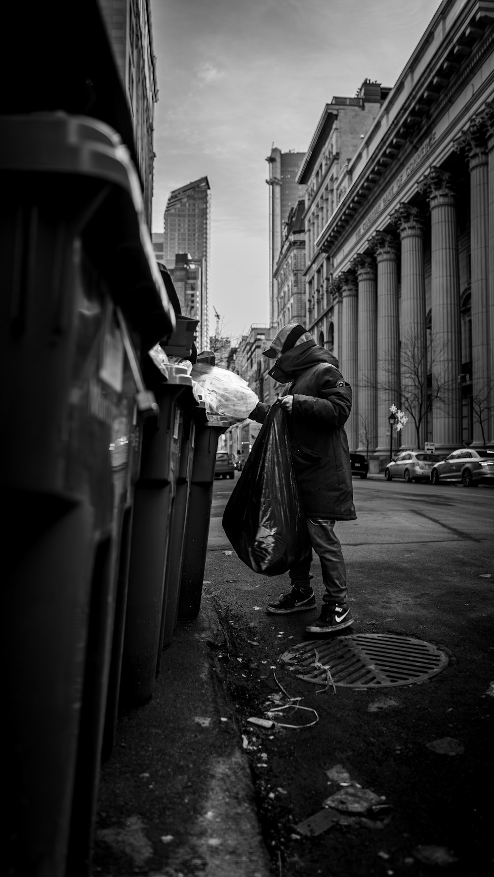 a black and white photo of a person picking up trash