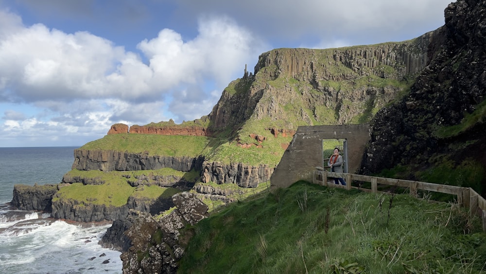 a man standing on the edge of a cliff next to the ocean