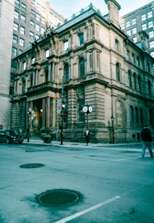 a man walking across a street next to a tall building