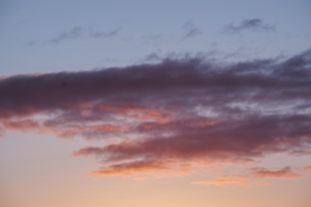 a plane flying in the sky at sunset