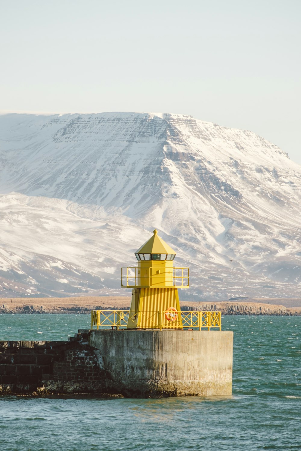 a yellow light house sitting on top of a pier