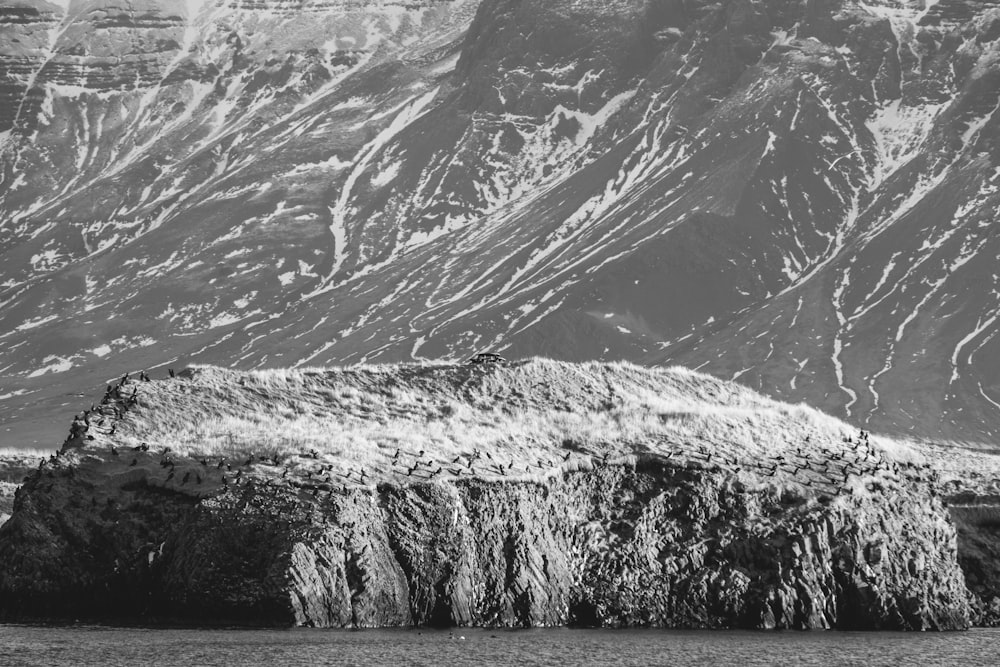 Una foto in bianco e nero di una formazione rocciosa di fronte a una montagna