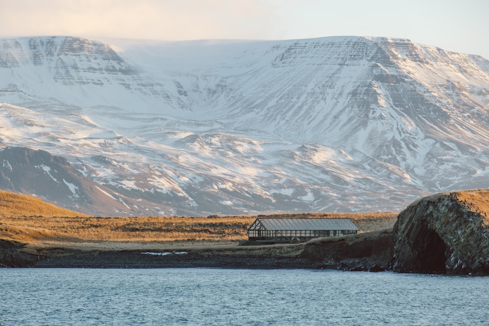 a house sitting on the side of a mountain next to a body of water