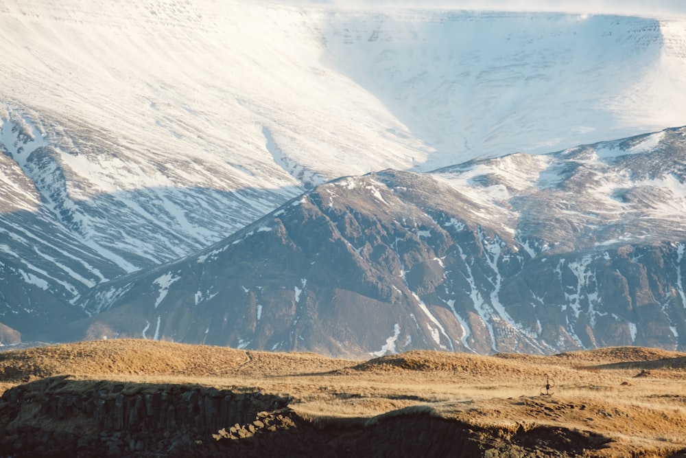 a mountain range covered in snow and brown grass