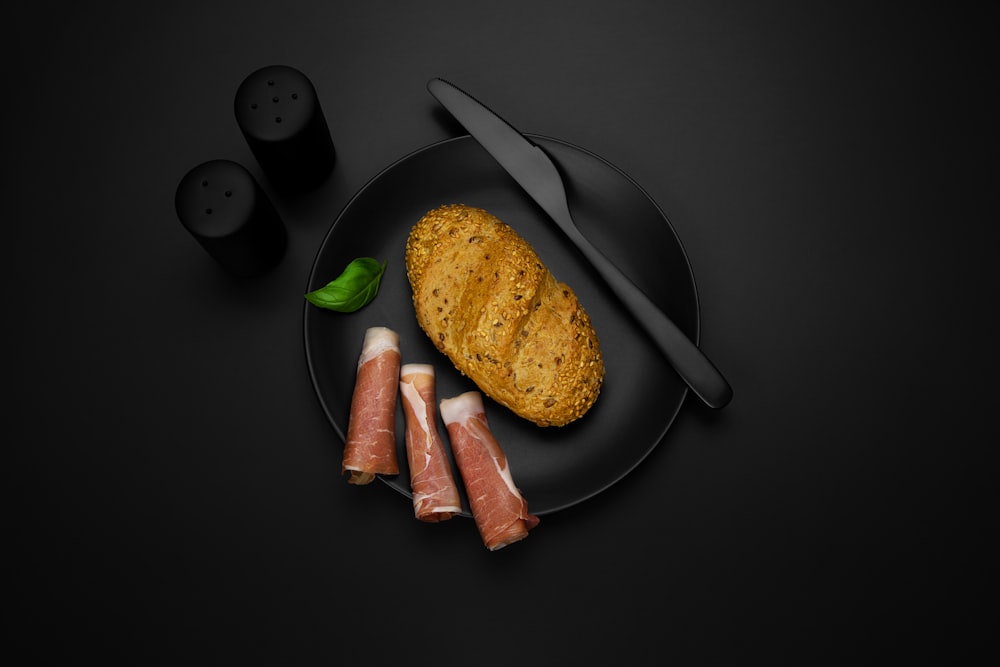 une assiette noire avec de la viande et un couteau dessus