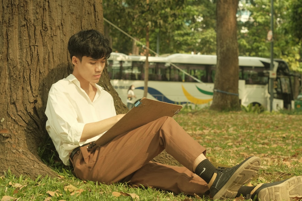 a man sitting under a tree reading a book