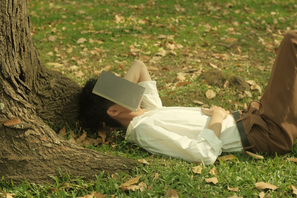 a man laying on the ground next to a tree