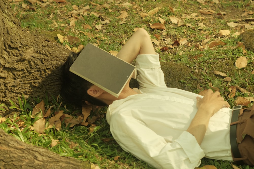 a man laying on the ground with a laptop on his head