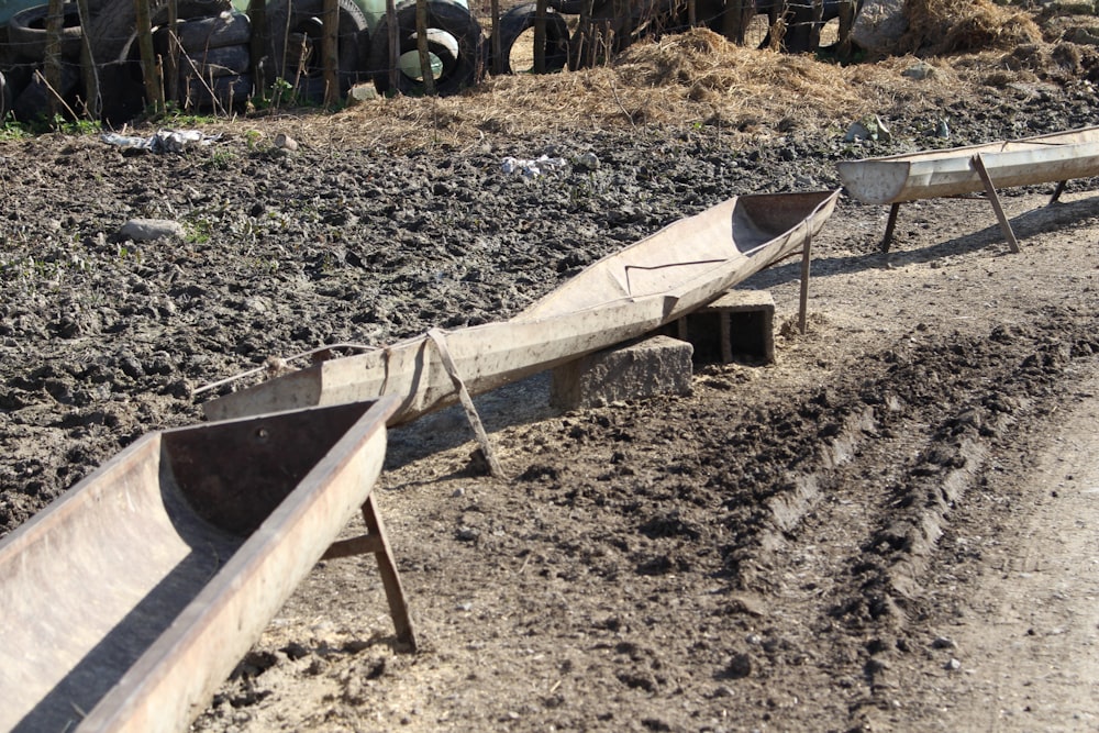 a row of wooden boats sitting on top of a dirt field