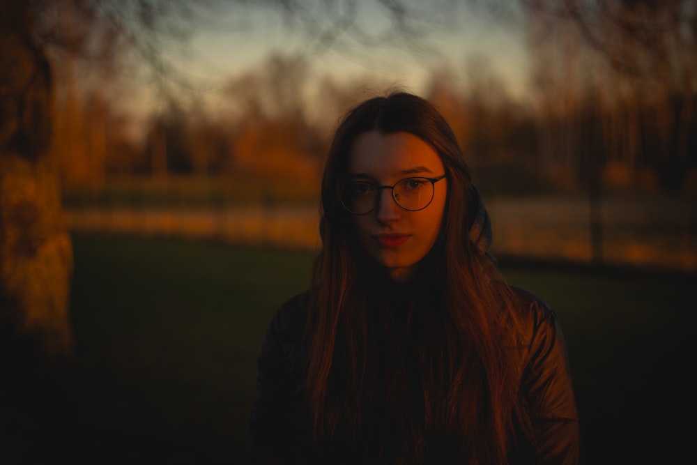 a woman with glasses standing in front of a tree