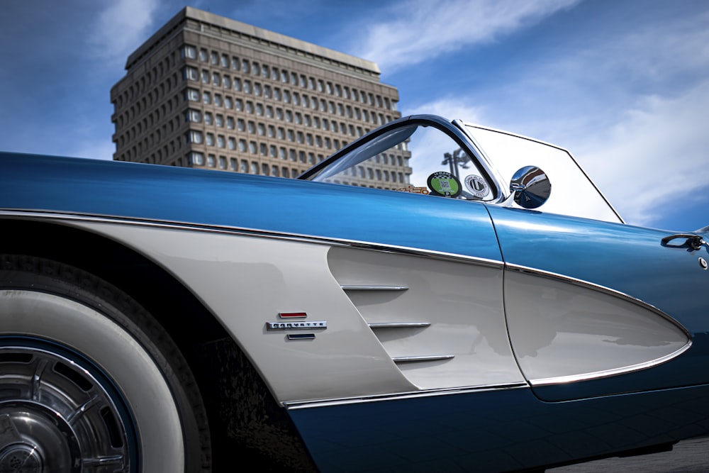 a blue and white car parked in front of a tall building