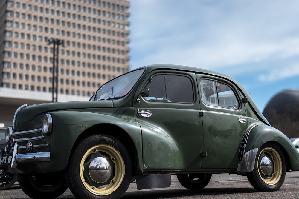 an old green car parked in a parking lot